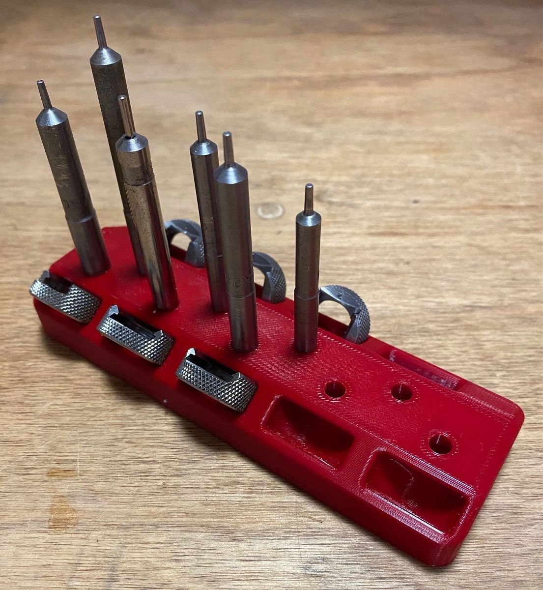 Red bench rack holding LEE case length gauges with shell holders in the matching slots