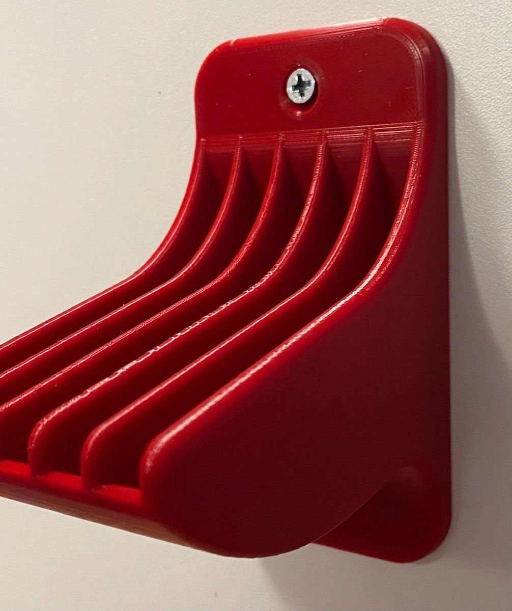 Empty red wall-mount shell plate rack with 5 slots, screwed to a wall